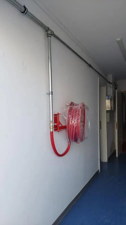 Fire hose reel and galvanised supply pipe in a corridor