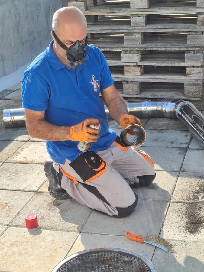 Technician cleaning stainless-steel flue pipes